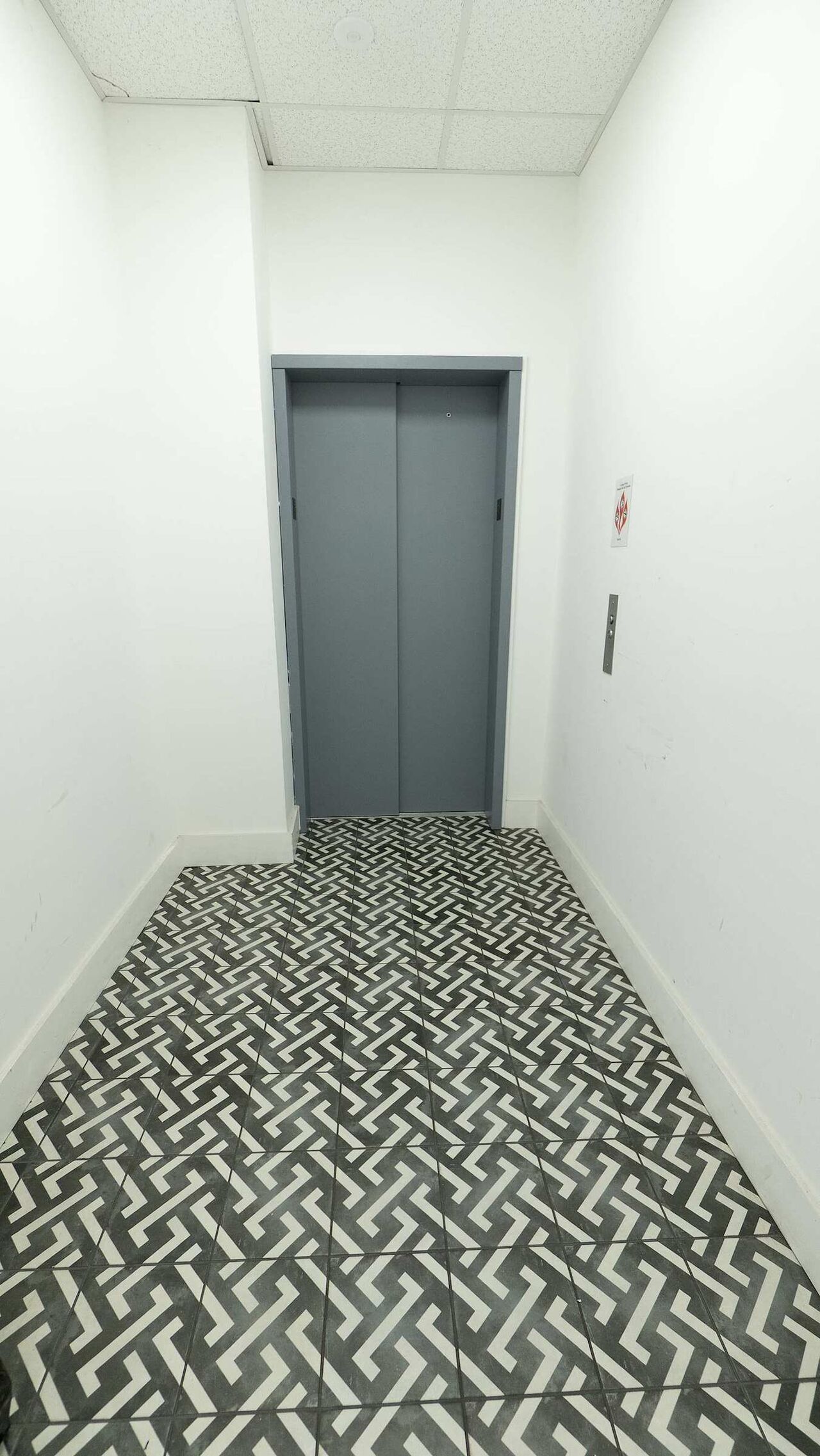The ground-floor lobby: a patterned tile floor leading to the elevator up to the second floor